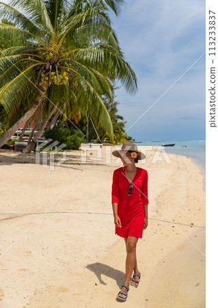 Travel woman walking on beach smiling in sundress and sunhat on Matira Beach, Bora Bora, Tahiti, French Polynesia. Image is unretouched and model is without makeup. Real people. Raw Image 113233837