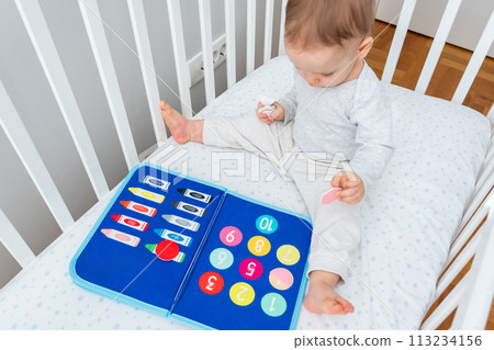 Baby happily plays with felt board in crib Baby happily plays with felt board in crib 113234156