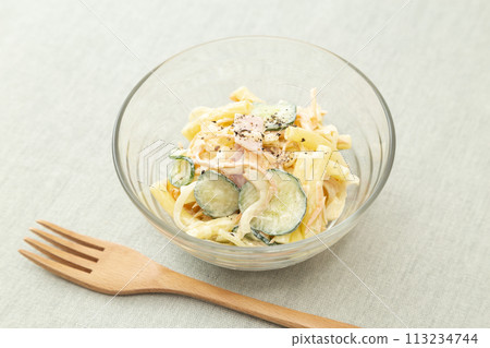A wooden spoon and macaroni salad placed on a placemat A wooden spoon and macaroni salad placed on a placemat 113234744