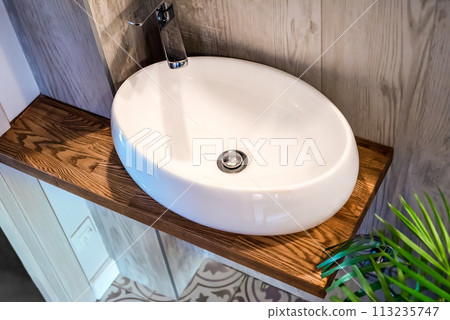 Bathroom design with white sink and wooden shelf close up 113235747