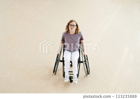 High angle view long shot of young Caucasian female wheelchair dancer with disability in spacious room 113235889