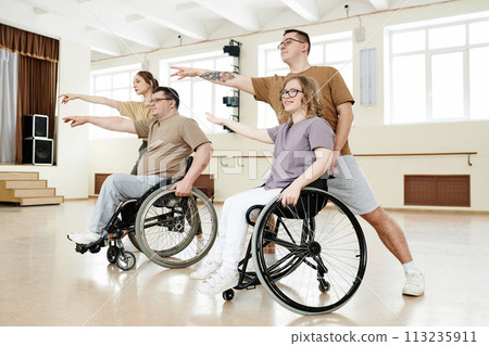 Group of four diverse Caucasian men and women practicing dance with wheelchairs in studio, long shot 113235911