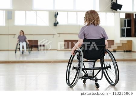 Selective focus rear view shot of unrecognizable young woman with disability in wheelchair practicing dance 113235969