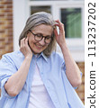 An older woman wearing glasses and a blue shirt. 113237202