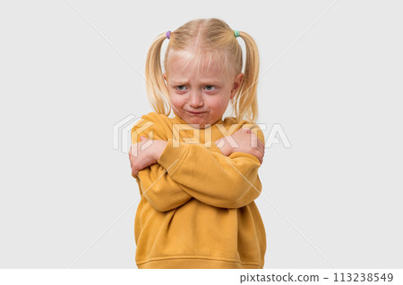 Portrait of sad little girl with blond hair in a yellow sweater. Isolated on white background. Portrait of sad little girl with blond hair in a yellow sweater. Isolated on white background. 113238549