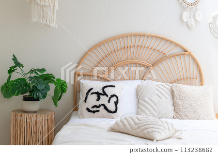 White pillows on wooden weave bed in minimal bedroom interior with green plants. Real photo 113238682