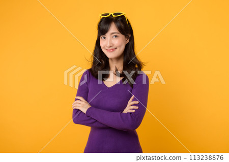 A confident and stylish businesswoman, wearing a purple shirt and sunglasses against a yellow background, exudes positivity and success with her cheerful smile and folded arms. A confident and stylish businesswoman, wearing a purple shirt and sunglasses against a yellow background, exudes positivity and success with her cheerful smile and folded arms. 113238876