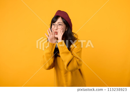 Get ready for the news! A trendy woman, in a red beret and yellow sweater, screams an announcement against a yellow backdrop. 113238923