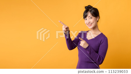 Look. Young pretty 30s asian woman wearing purple shirt and sunglasses expression pointing finger to free copy space for showing product isolated on yellow background. Advertisement concept. Look. Young pretty 30s asian woman wearing purple shirt and sunglasses expression pointing finger to free copy space for showing product isolated on yellow background. Advertisement concept. 113239033