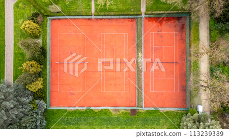 Aerial View of Twin Red Clay Tennis Courts Surrounded by Greenery Aerial View of Twin Red Clay Tennis Courts Surrounded by Greenery 113239389
