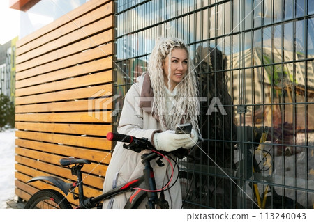 Woman Standing Next to Bike by Building 113240043