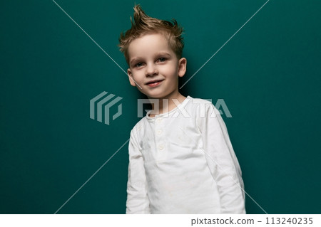 Young Boy Standing in Front of Green Wall 113240235