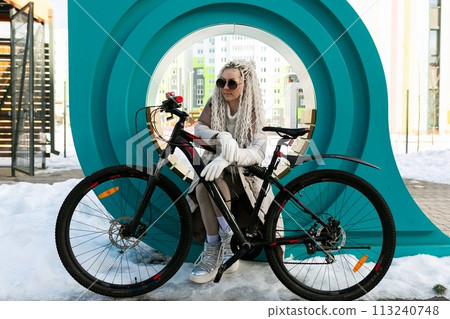 Woman Sitting on Bench Next to Bike 113240748