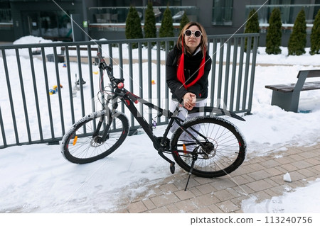 A woman rented a bicycle to ride around the city in winter. 113240756