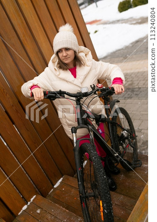 Woman in White Coat and Hat Standing Next to Bike Woman in White Coat and Hat Standing Next to Bike 113240804