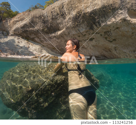 Woman on tropical vacation paradise on sea. Summer sea joy in Turkish seacoast, beaches along Lycian Way, Turkish Riviera. Asian female underwater and turquoise ocean around. 113241256