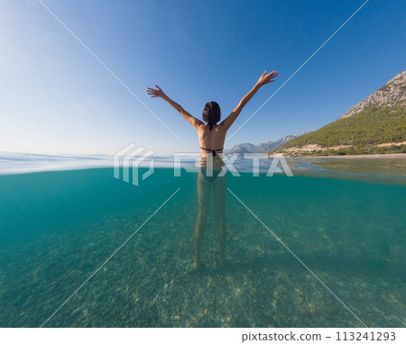 Woman on tropical vacation paradise on sea. Summer sea joy in Turkish seacoast, beaches along Lycian Way, Turkish Riviera. Asian female underwater and turquoise ocean around. Woman on tropical vacation paradise on sea. Summer sea joy in Turkish seacoast, beaches along Lycian Way, Turkish Riviera. Asian female underwater and turquoise ocean around. 113241293