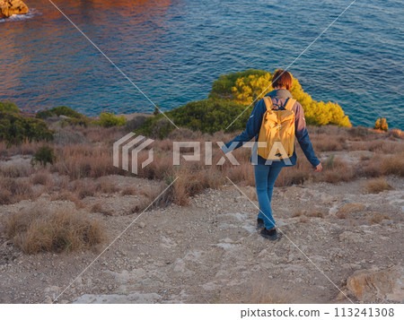 Young woman hiking on rocky beach in Spain, Benidorm. Watching the choppy sea and the bay. traveler enjoying freedom in serene nature landscape Young woman hiking on rocky beach in Spain, Benidorm. Watching the choppy sea and the bay. traveler enjoying freedom in serene nature landscape 113241308