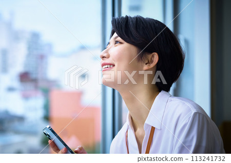 A young business woman operating a smartphone in the office 113241732