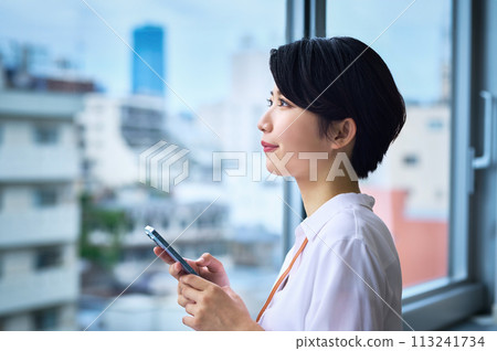 一位年輕的女商人在辦公室操作智能手機 113241734