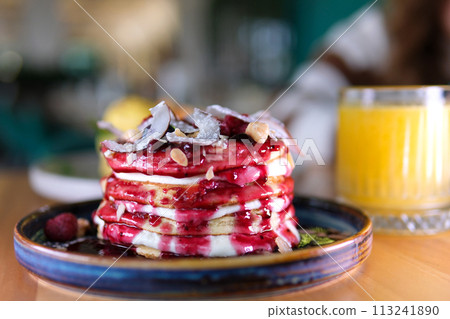 stack of delicious pancake decorated with coconut flakes blueberries hazelnuts almond flakes raspberries and jam delicious breakfast with sour cream eaten with fork in restaurant beautiful serving stack of delicious pancake decorated with coconut flakes blueberries hazelnuts almond flakes raspberries and jam delicious breakfast with sour cream eaten with fork in restaurant beautiful serving 113241890