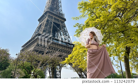 a girl with a white parasol stands against the backdrop of the Eiffel Tower with her back to us can be used for advertising for the Internet for travel agencies a girl with a white parasol stands against the backdrop of the Eiffel Tower with her back to us can be used for advertising for the Internet for travel agencies 113242079