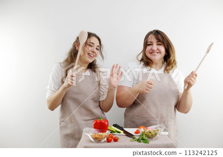 2 women dancing while preparing tasty and healthy food vegetarian vegetable saladdaughter-in-law mother-in-law friendly family place for text advertising grocery store healthy food delivery 113242125