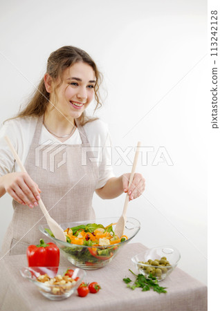 Smiling young woman serving fresh salad on plate Green vegan salad with mixed green leaves and vegetables tomatoes and fresh Healthy vegetable salad of fresh tomato, cucumber, onion, spinach, 113242128