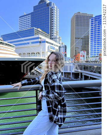 A young girl stands against the background of Canada Place against the backdrop of a cruise liner The skyscrapers of Vancouver Canada are visible in the background her hair is curly A young girl stands against the background of Canada Place against the backdrop of a cruise liner The skyscrapers of Vancouver Canada are visible in the background her hair is curly 113242217