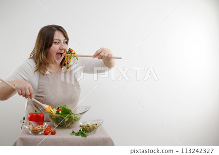 funny cheerful woman eating salad wooden spoon stuffs portion of food weight loss advertising healthy food vegetarian food woman in body full juicy banner white background glassware good appetite 113242327