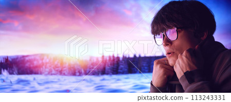 Young man wearing glasses, standing with thoughtful expressing on winter sunset, snowy landscape. Young man wearing glasses, standing with thoughtful expressing on winter sunset, snowy landscape. 113243331
