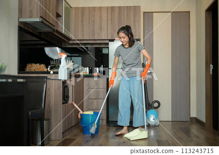 Happy young woman enjoy household chores cleaning floor in kitchen Happy young woman enjoy household chores cleaning floor in kitchen 113243715