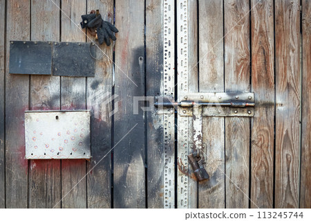 Wooden plank gate door with locks, post box and metal plate and shadows on a sunny day Wooden plank gate door with locks, post box and metal plate and shadows on a sunny day 113245744