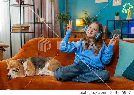 Trendy cheerful positive child girl having fun dancing moving to rhythm embracing cute beagle dog 113245907