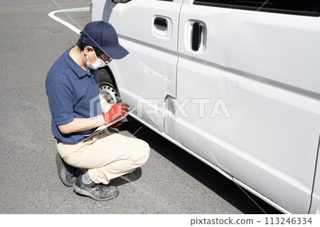 A worker giving an estimate for repairing a damaged car 113246334