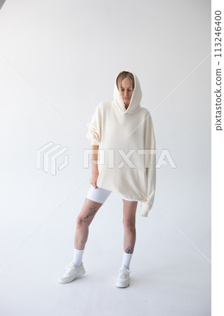 Beautiful blonde woman posing in white hoodie and leggings posing against white background 113246400