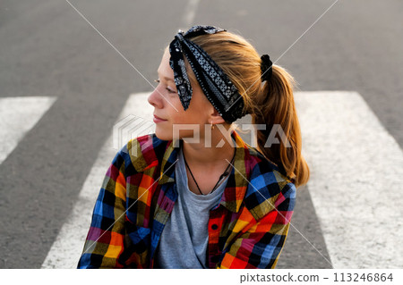 Portrait of a teenage girl wearing a stylish bandana and a cheerful smile, standing confidently on a country road, exuding youthfulness and a sense of adventure 113246864