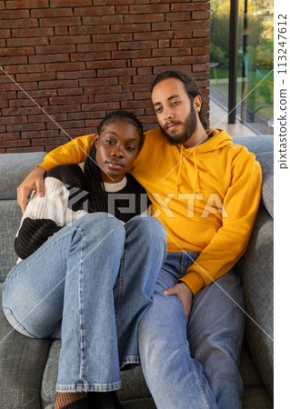 Comfortable Embrace: Multiethnic Couple Relaxing on Couch with Warmth and Style 113247612