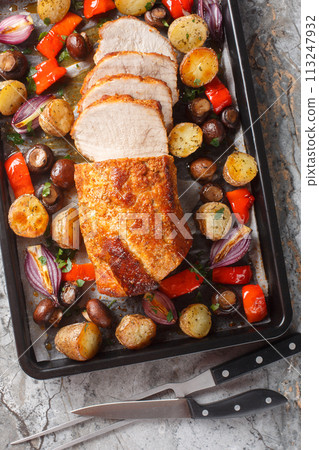 Flavor boosted pork loin baked together with potatoes, peppers, mushrooms and onions closeup on a baking sheet. Vertical top view Flavor boosted pork loin baked together with potatoes, peppers, mushrooms and onions closeup on a baking sheet. Vertical top view 113247932