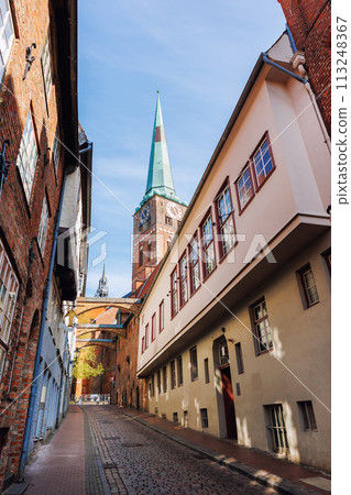 Scenic view old narrow european german Lubeck with red brick ancient houses vintage iron stained glass lamp lantern wall. Cityscape Lubeck UNESCO heritage city altstadt in Germany travel destination Scenic view old narrow european german Lubeck with red brick ancient houses vintage iron stained glass lamp lantern wall. Cityscape Lubeck UNESCO heritage city altstadt in Germany travel destination 113248367