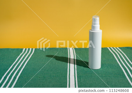 Blank white sunscreen bottle on green Turkish beach towel in direct sunlight. Summer skin protection mockup template with reading beach aesthetic Blank white sunscreen bottle on green Turkish beach towel in direct sunlight. Summer skin protection mockup template with reading beach aesthetic 113248608