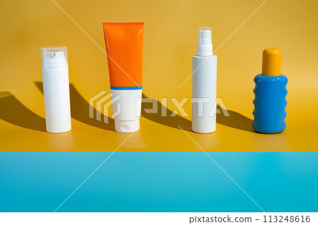 Different blank sunscreen packaging bottles on minimalist beach of yellow and blue paper in direct sunlight. Summer skin protection mockup template Different blank sunscreen packaging bottles on minimalist beach of yellow and blue paper in direct sunlight. Summer skin protection mockup template 113248616