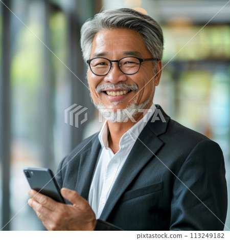 Smiling Asian businessman 50-60 years old, active business man against the background of his office Smiling Asian businessman 50-60 years old, active business man against the background of his office 113249182