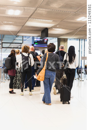 Woman with luggage standing in a line at airport. Woman with luggage standing in a line at airport. 113249381