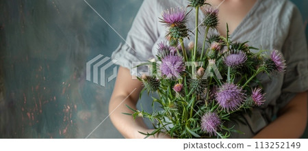 a woman holds a bouquet of thistles 113252149