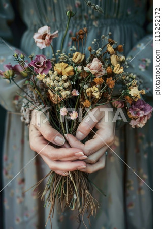 A woman tender grasp on a bouquet of dried flowers 113252172