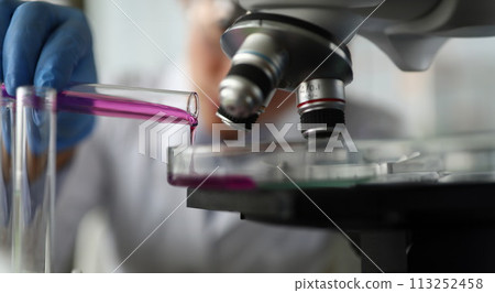 Assistant pouring liquid into flask Assistant pouring liquid into flask 113252458