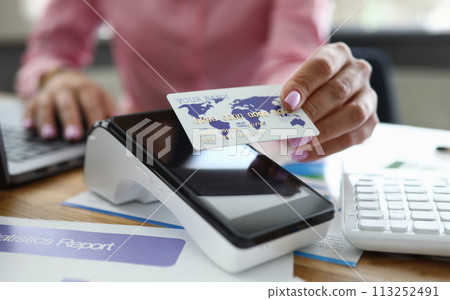 Girl at table holds credit card over bank terminal Girl at table holds credit card over bank terminal 113252491
