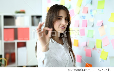 Cheerful female clerk showing all right symbol with her fingers at office workplace 113252510