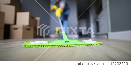 Male hand with yellow protective gloves hold green plastic mop Male hand with yellow protective gloves hold green plastic mop 113252533